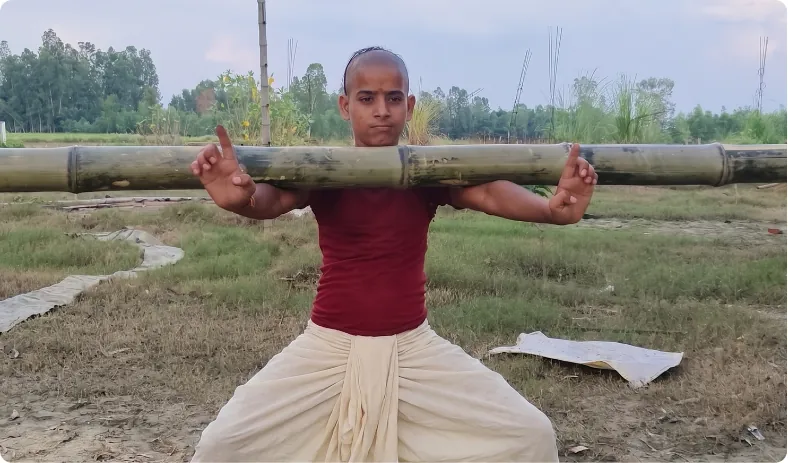 Youth balancing a bamboo pole across his shoulders in a field