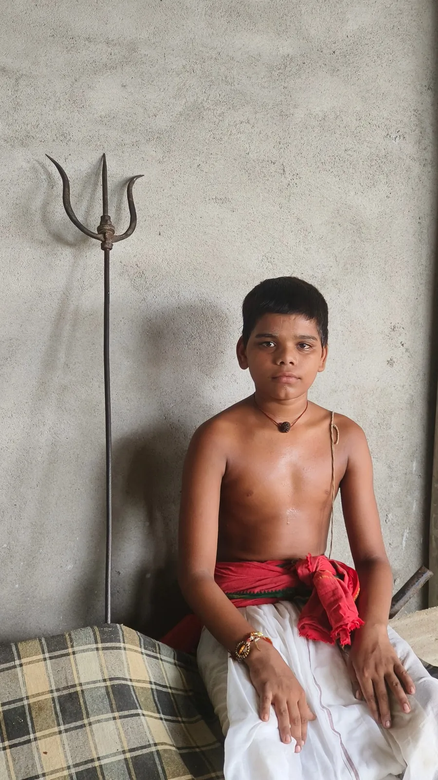 Student seated beside a trishul in the gurukul