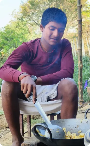 Student cooking food in a wok outdoors